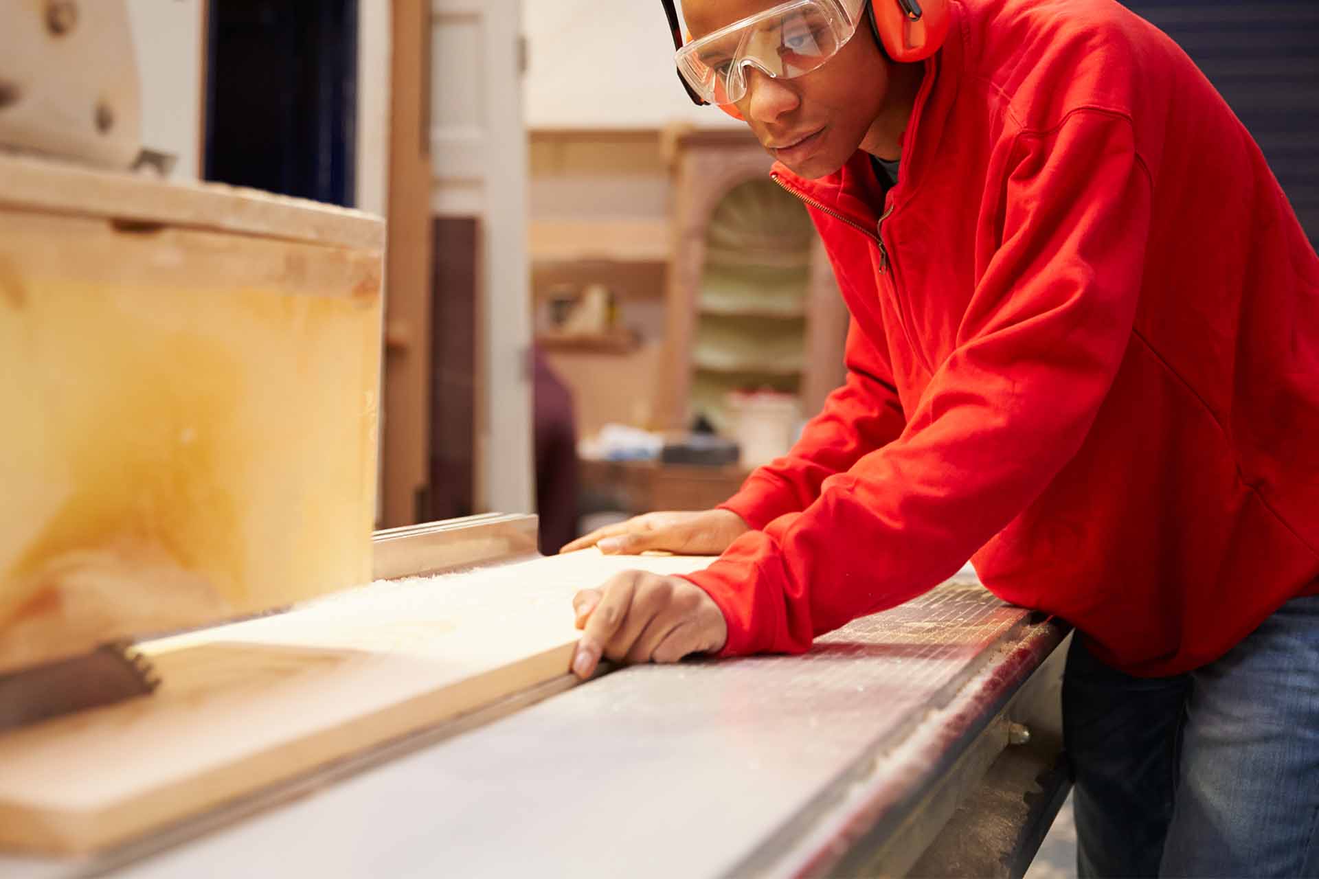 A tradesperson measuring up a plank of wood before sawing it in half