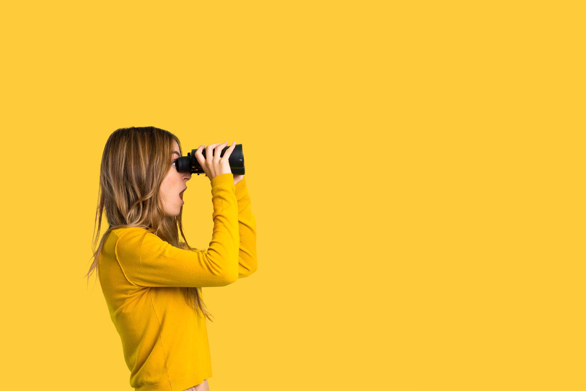 A girl in a yellow jumper looking through binoculars against a yellow background.