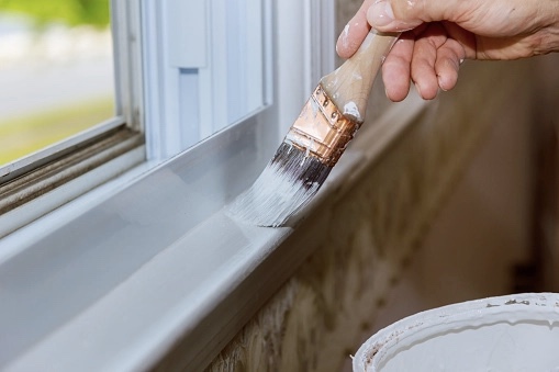 Person painting window sill