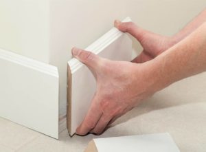 Person fitting skirting board on a corner