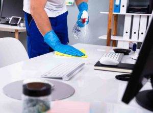 cleaner disinfecting an office desk