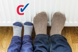 Two pairs of feet pressed against a radiator
