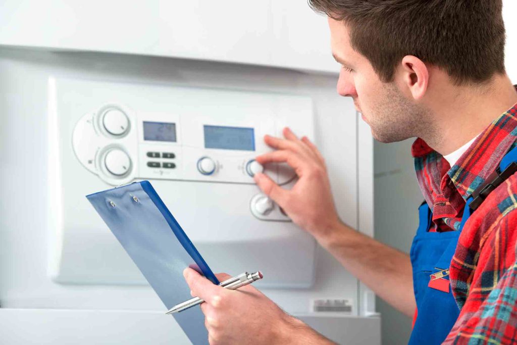 A gas engineer checking a gas boiler with a clipboard