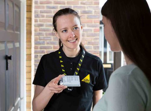 Gas safe engineer stood at a door with a customer holding up her gas safe ID card