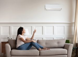 Woman using air conditioner from sofa