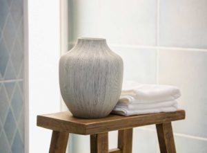 An earthern pot and towels on a wooden stool - Small rustic bathroom ideas on a budget