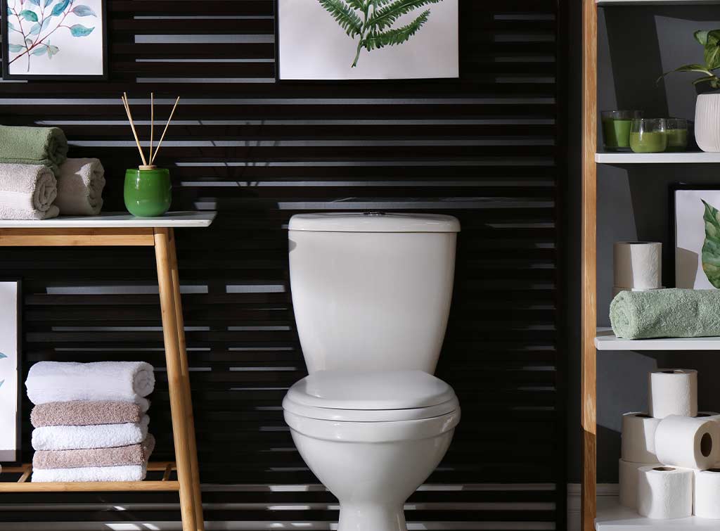 A bathroom with black walls and a painting hanging over the toilet - Wall art as a cheap small bathroom makeover idea