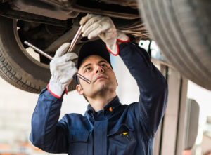 Male mechanic fixing underside of a vehicle