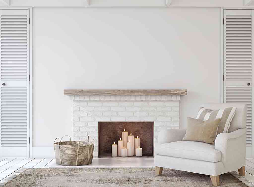 A closed white fireplace with a display of candles - cheap fireplace ideas for storage and display