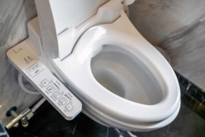 A smart toilet with a remote mounted next to it - Smart toilet cost