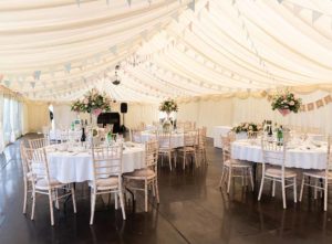 Marquee wedding tables and chairs on a wooden floor - wedding marquee hire cost