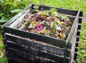 Step for how to build a compost bin. Image: Wooden compost bin filled with waste materials.
