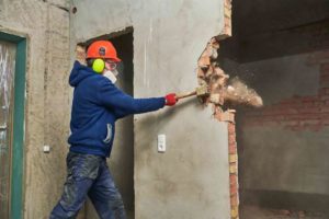 Builder breaking down a wall during house renovation - how much does it cost to flip a house?