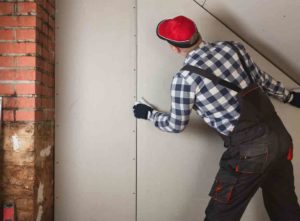 Tradesperson replacing water stained drywall