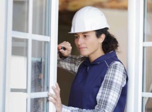 Female double glazing installer fitting a door