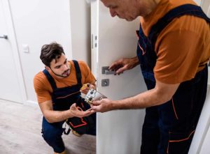 Two locksmiths repairing a door lock