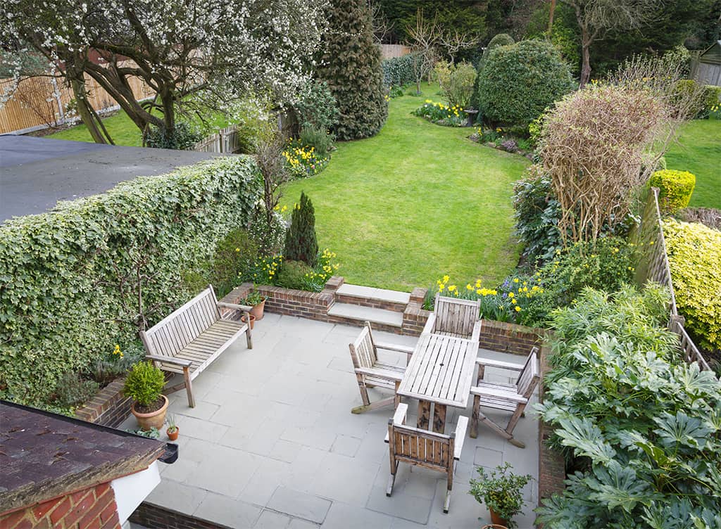 A raised concrete patio with wooden garden furniture
