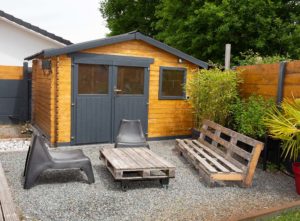 Building your perfect summer house: Lovely patio area with wood and black painted summer house with pitched roof
