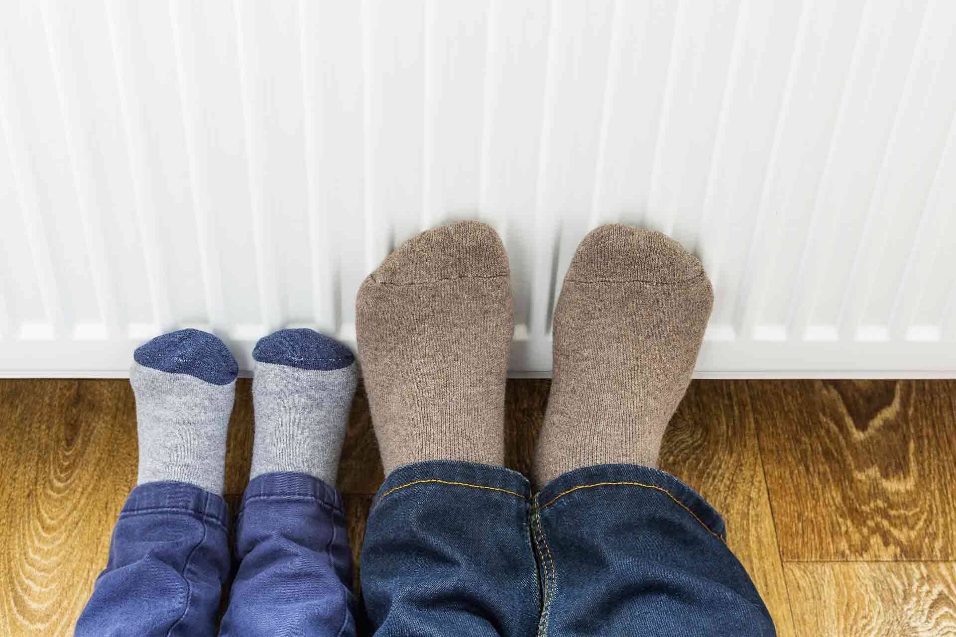 Image of a parent and their child with their feet on the radiator for the Checkatrade blog: The most efficient way to heat a house