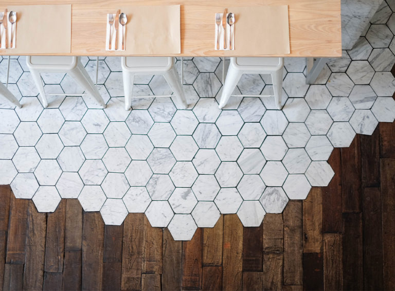 Two-toned kitchen floor with dark wood and white hexagon tiles bleeding into each other.