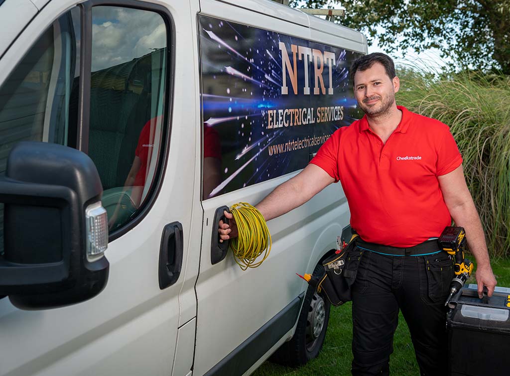 Electrician with electrical cable and toolbox next to his work van