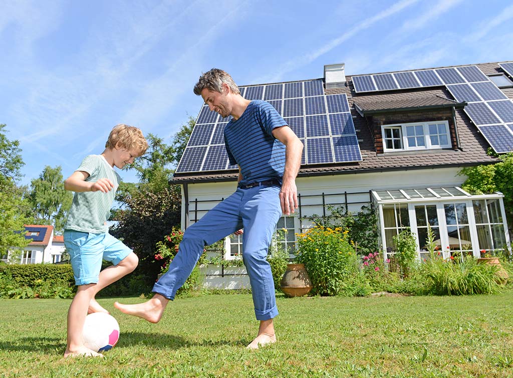 Father and son playing football in the garden during summer