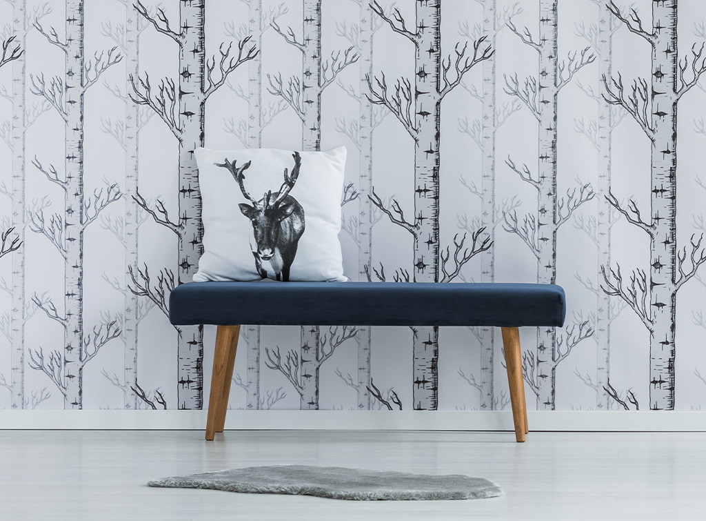 Polished concrete hallway flooring with silver birch wallpaper and a deer cushion on a blue accent bench