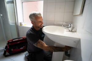 Bathroom fitter installing a bathroom sink waste pipe