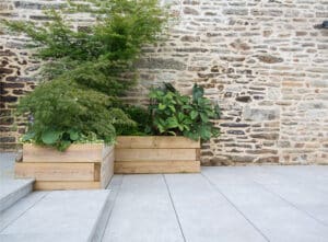 Grey patio against rustic brick wall with boxed in planting
