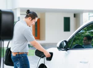 Homeowner plugging in his electric vehicle to an EV charger at home
